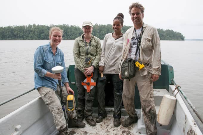 Four people (3 women and a man) stand in a research boat with field instruments